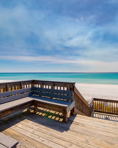 Wooden beach deck with built-in seating overlooking turquoise ocean and white sand beach