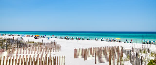 White sand beach with colorful umbrellas and emerald water