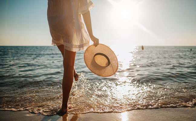 Woman in a straw hat walking along the shoreline on a sunny day