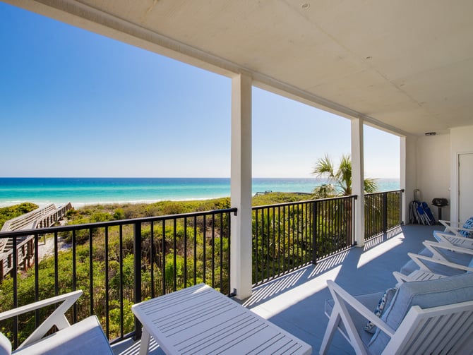 Beachfront deck with lounge chairs overlooking turquoise ocean, white sand beach, and coastal vegetation
